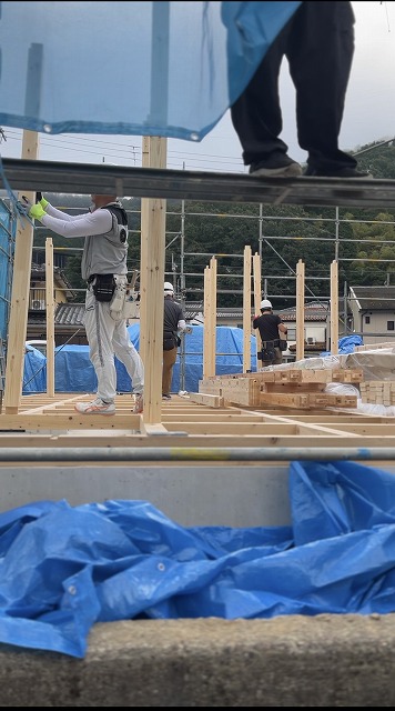 舞鶴市の新築注文住宅の上棟工事で柱を立てる大工たちの作業風景